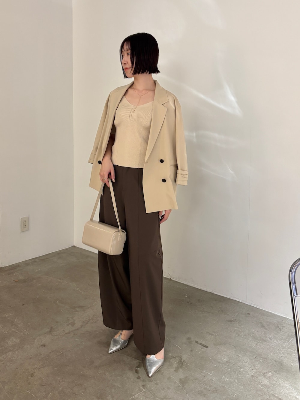 シルバー系のパンプス、ブラウン系のその他パンツ、ベージュ系のテーラードジャケットを着用したレディースの春コーディネートの2枚目の写真