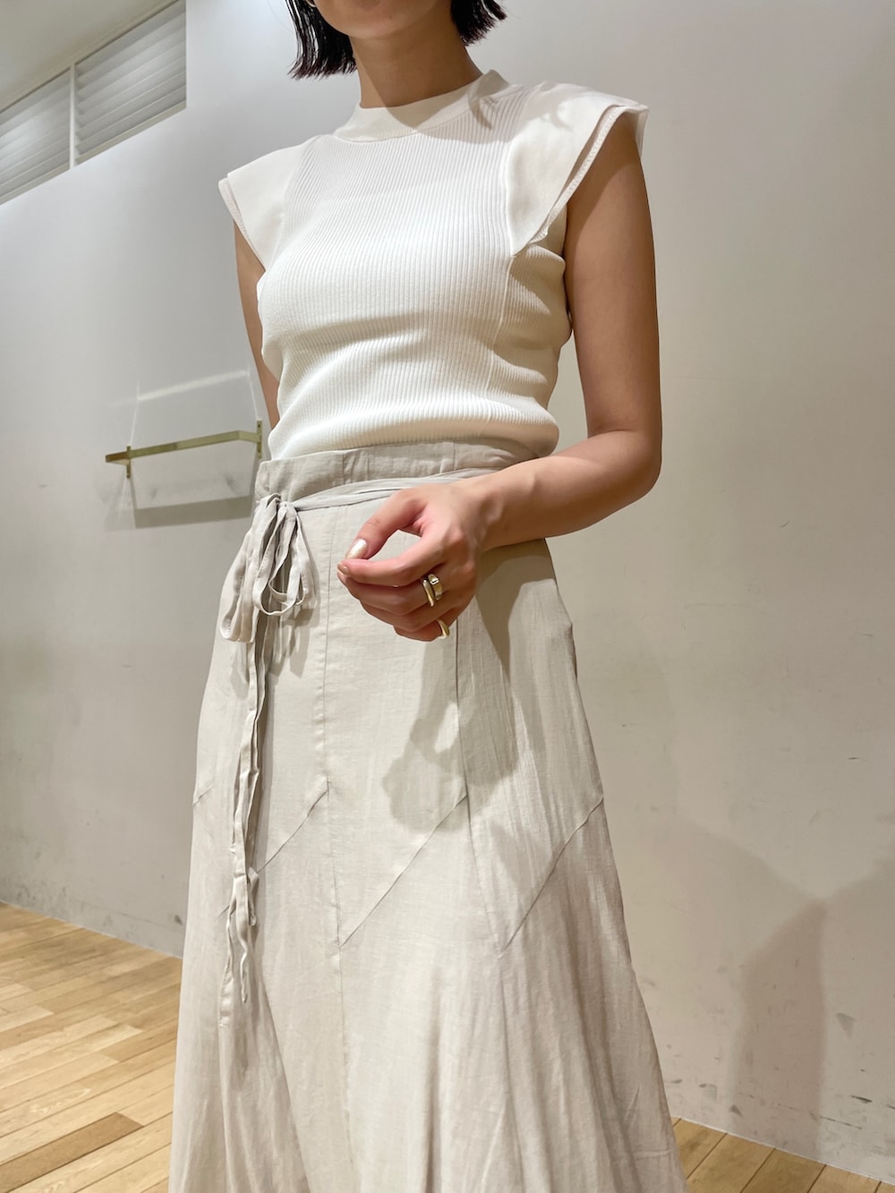 イエロー系のサンダル、グレー系のスカート、ホワイト系のニット/セーターを着用したレディースの夏コーディネートの7枚目の写真