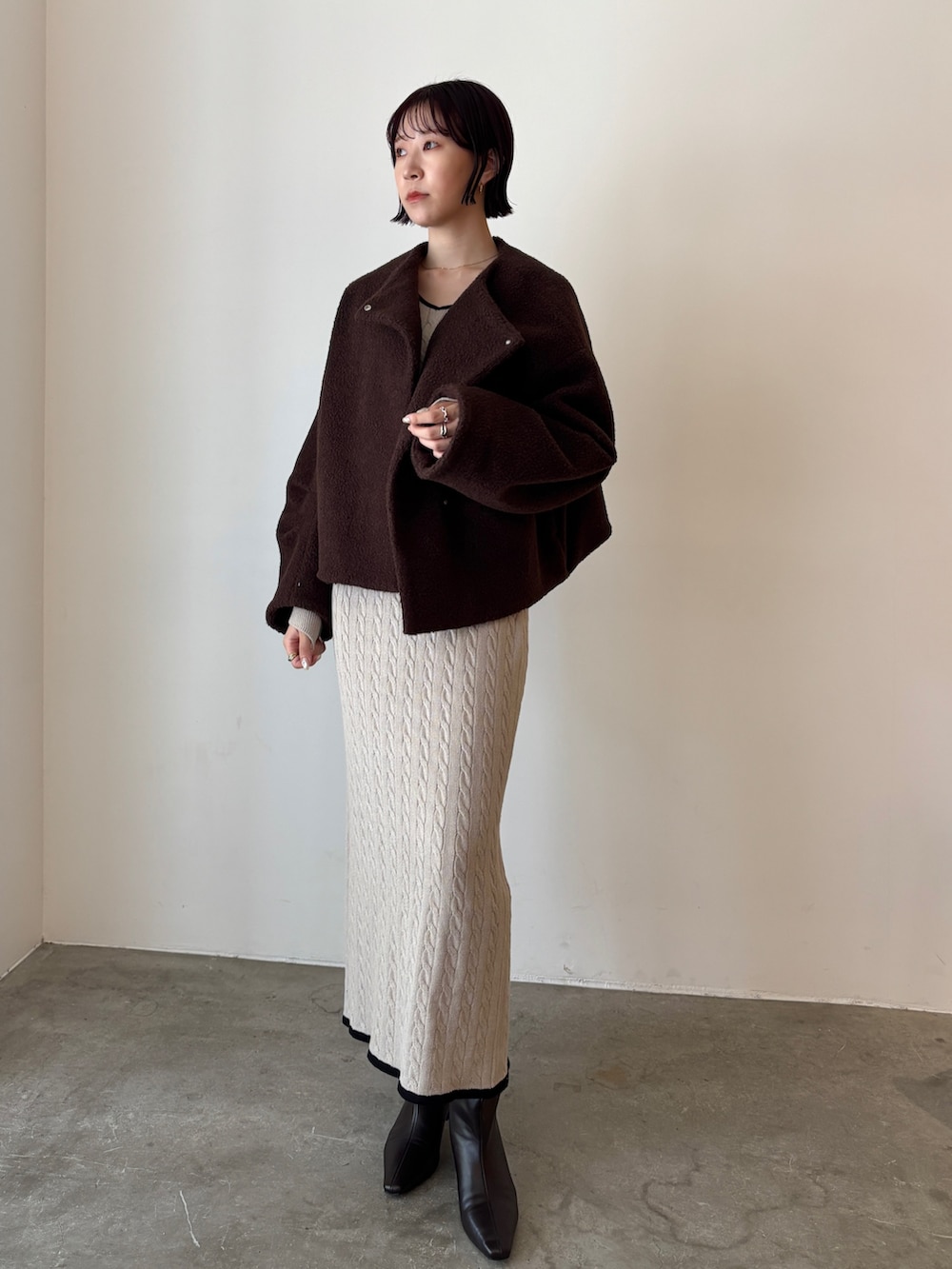 ベージュ系のワンピース、ブラウン系のブルゾン、ブラウン系のブーツを着用したレディースの秋コーディネートの6枚目の写真