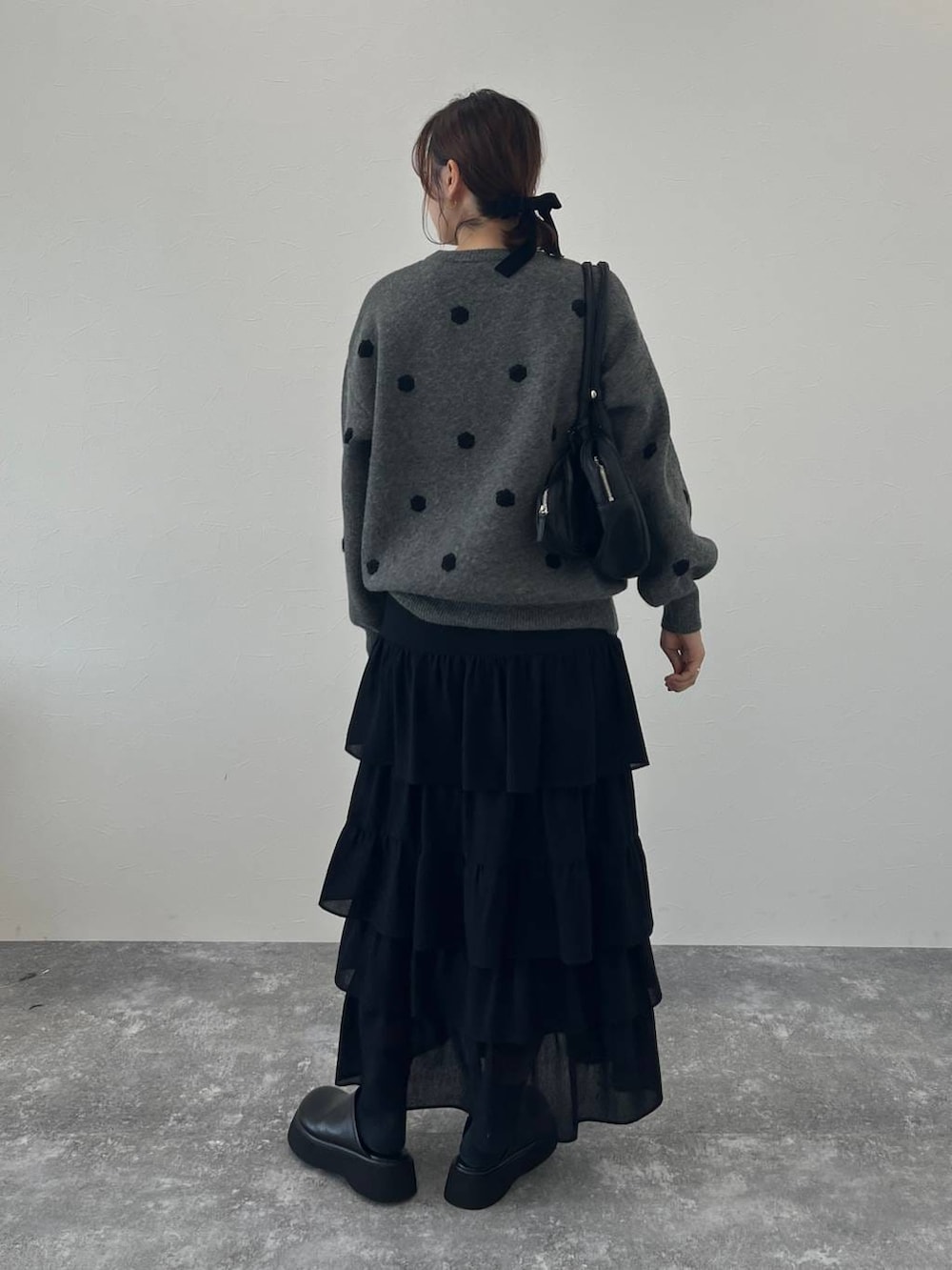 ブラック系のサンダル、ブラック系のスカート、グレー系のニット/セーターを着用したレディースの冬コーディネートの3枚目の写真