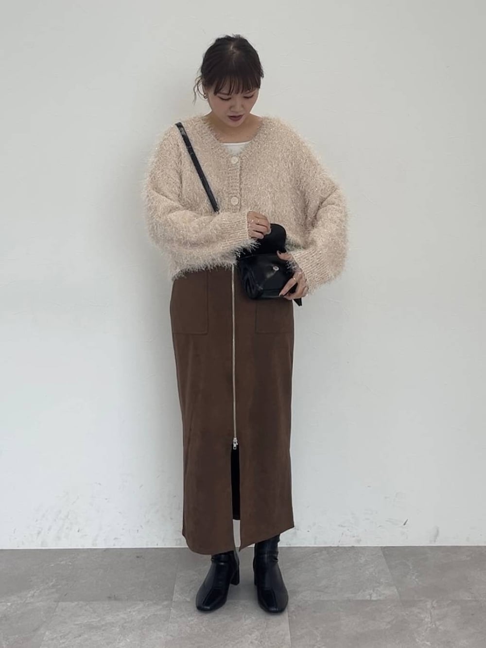 ブラック系のブーツ、ブラウン系のスカート、ベージュ系のカーディガン/ボレロを着用したレディースの秋コーディネートの2枚目の写真