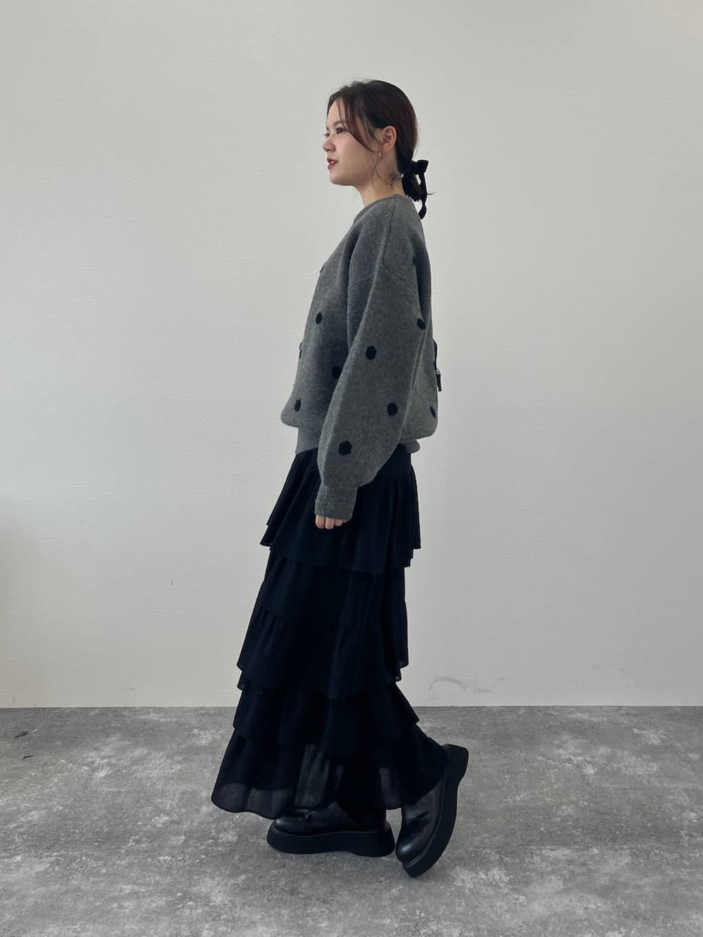 ブラック系のサンダル、ブラック系のスカート、グレー系のニット/セーターを着用したレディースの冬コーディネートの2枚目の写真