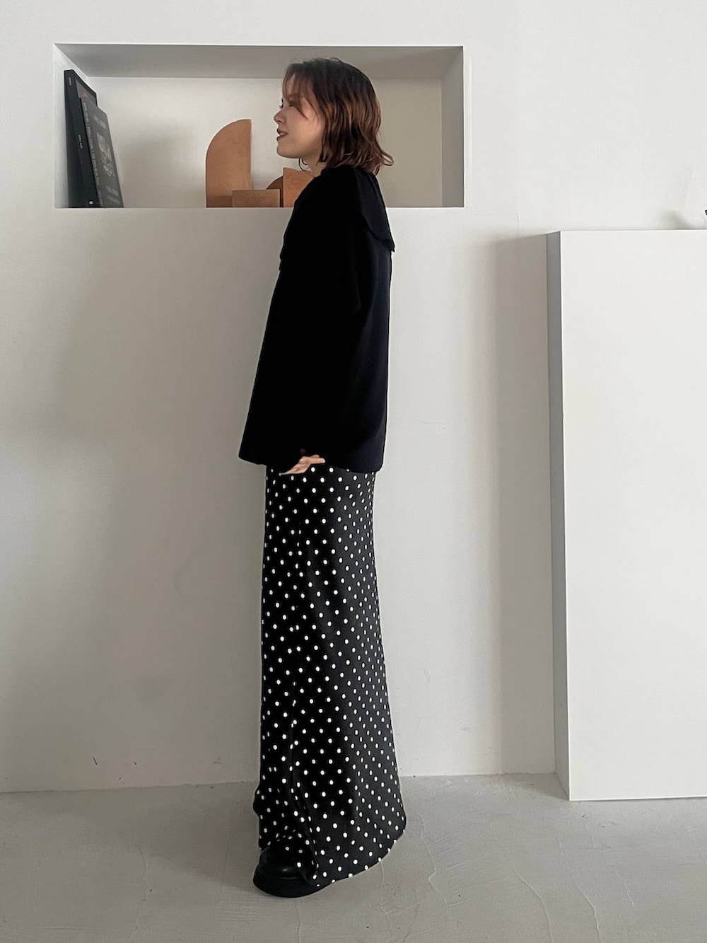 ブラック系のスカート、ブラック系のサンダル、ブラック系のニット/セーターを着用したレディースの秋コーディネートの2枚目の写真