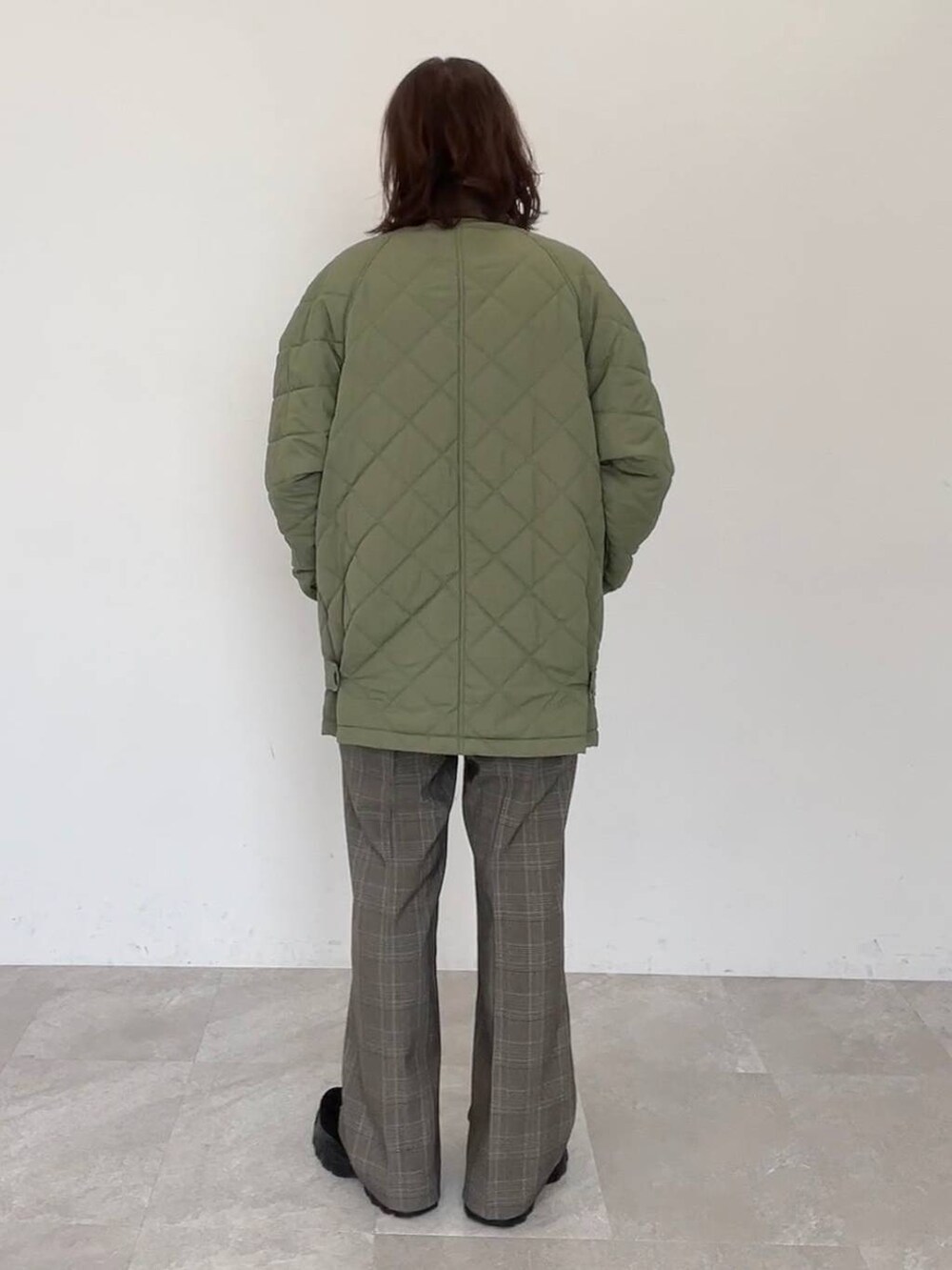 グリーン系のブルゾン、ブラウン系のスラックス、ベージュ系のニット/セーターを着用したレディースの秋コーディネートの3枚目の写真