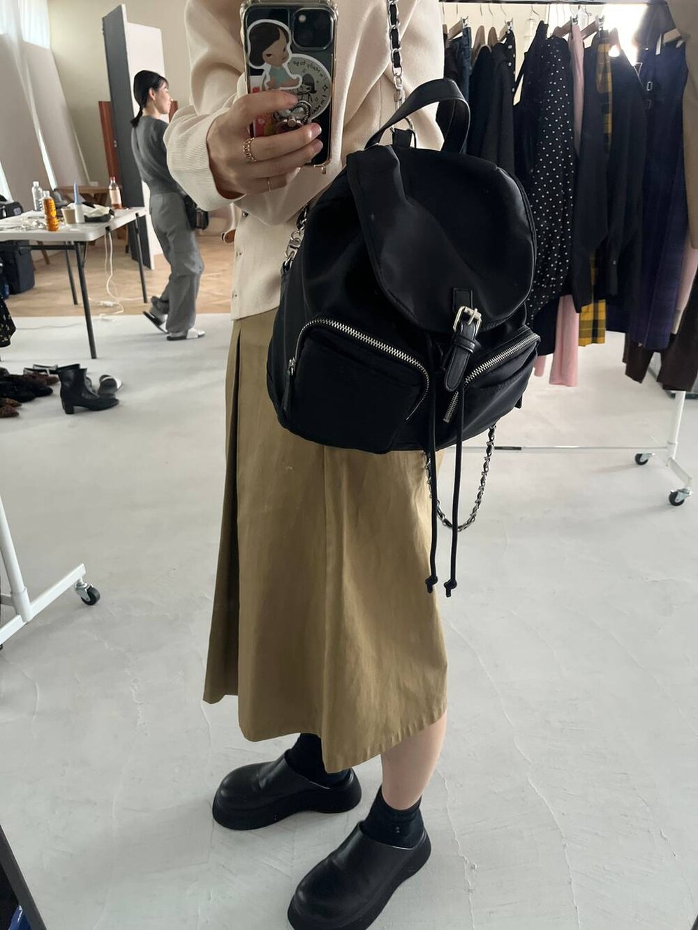 ベージュ系のチノパンツ、ブラック系のサンダル、ブラック系のショルダーバッグを着用したレディースの秋コーディネートの2枚目の写真