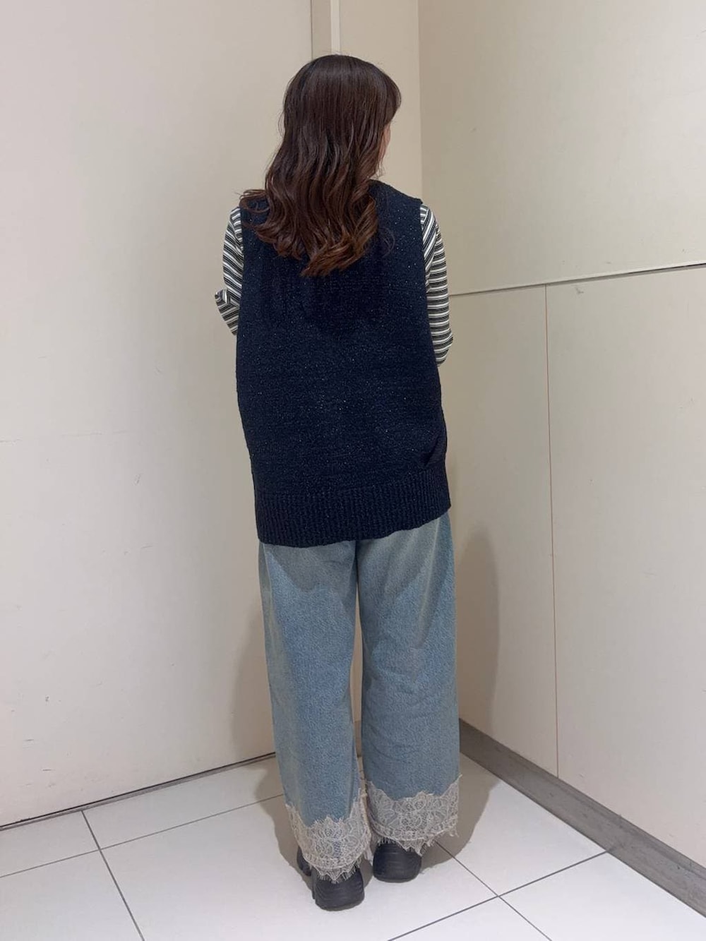 ホワイト系のショルダーバッグ、ブルー系のデニムパンツ、ブラウン系のローファーを着用したレディースの春コーディネートの3枚目の写真