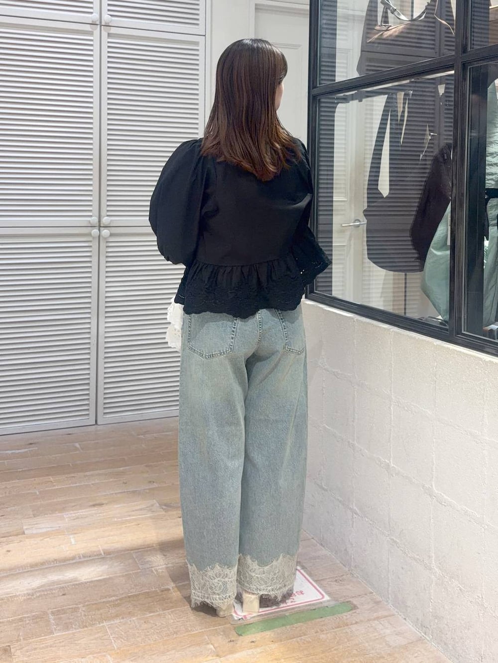 ブルー系のデニムパンツ、ブラック系のシャツ/ブラウス、ホワイト系のハンドバッグを着用したレディースの夏コーディネートの3枚目の写真