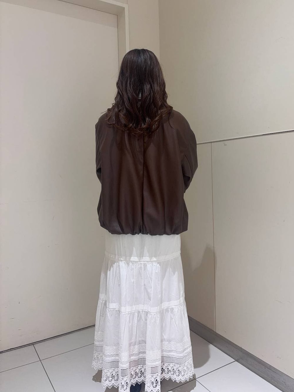 ホワイト系のショルダーバッグ、ブラック系のパンプス、ブラウン系のブルゾンを着用したレディースの春コーディネートの3枚目の写真