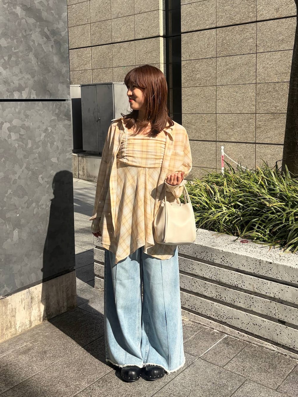 ホワイト系のショルダーバッグ、ブルー系のデニムパンツ、ブラック系のサンダルを着用したレディースの春コーディネートの2枚目の写真
