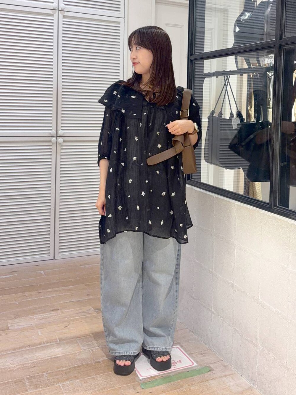 ブラック系のワンピース、ブルー系のデニムパンツ、ブラック系のサンダルを着用したレディースの夏コーディネートの2枚目の写真