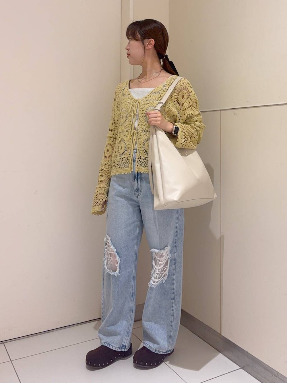 ホワイト系のショルダーバッグ、シルバー系のタンクトップ、ブルー系のデニムパンツを着用したレディースの春コーディネートの2枚目の写真