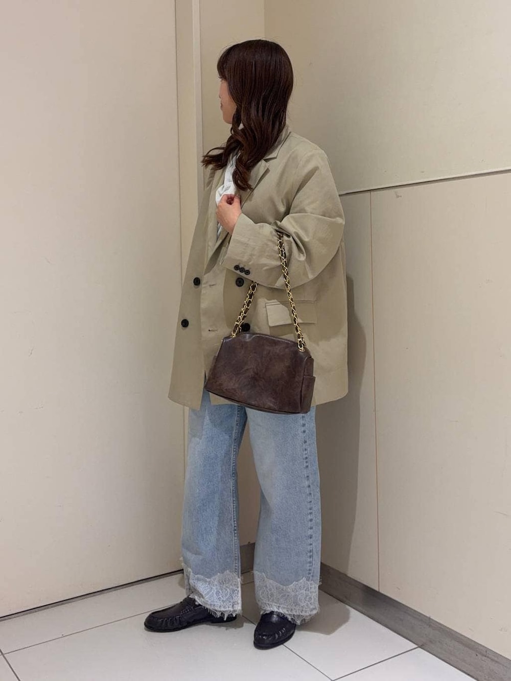 ブルー系のデニムパンツ、ブラック系のショルダーバッグ、ブラウン系のローファーを着用したレディースの春コーディネートの2枚目の写真