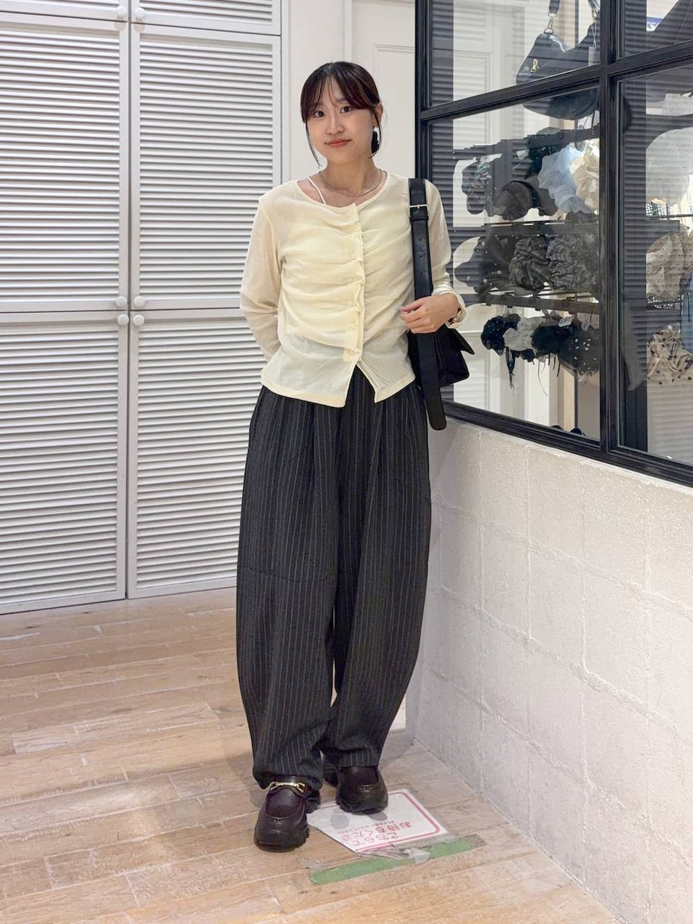 ブラック系のショルダーバッグ、ホワイト系のTシャツ/カットソー、ブラウン系のローファーを着用したレディースの秋コーディネートの2枚目の写真