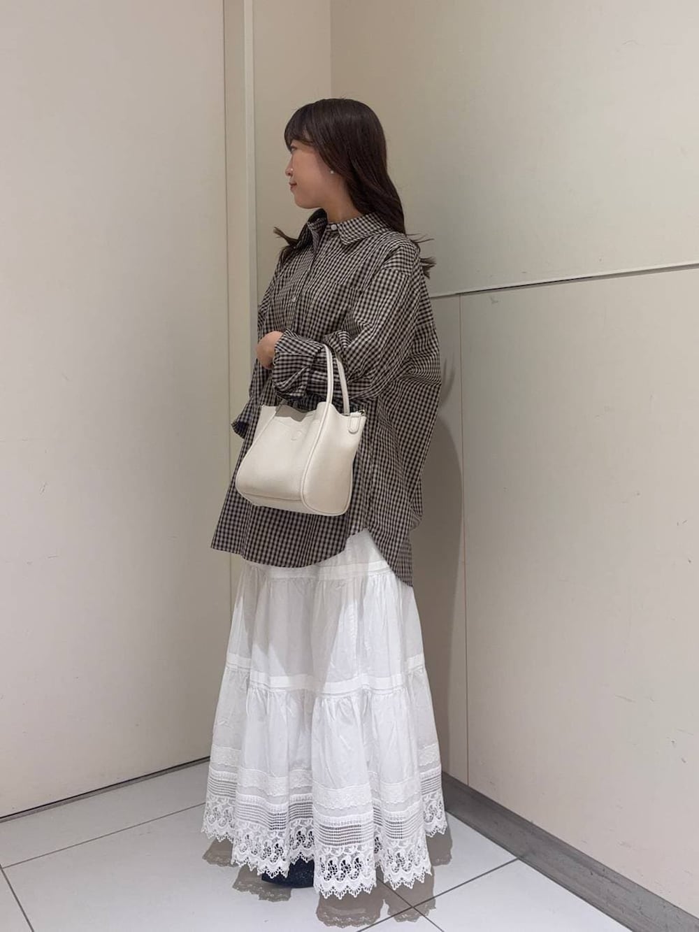 ホワイト系のショルダーバッグ、ブラック系のパンプス、ブラウン系のシャツ/ブラウスを着用したレディースの春コーディネートの2枚目の写真