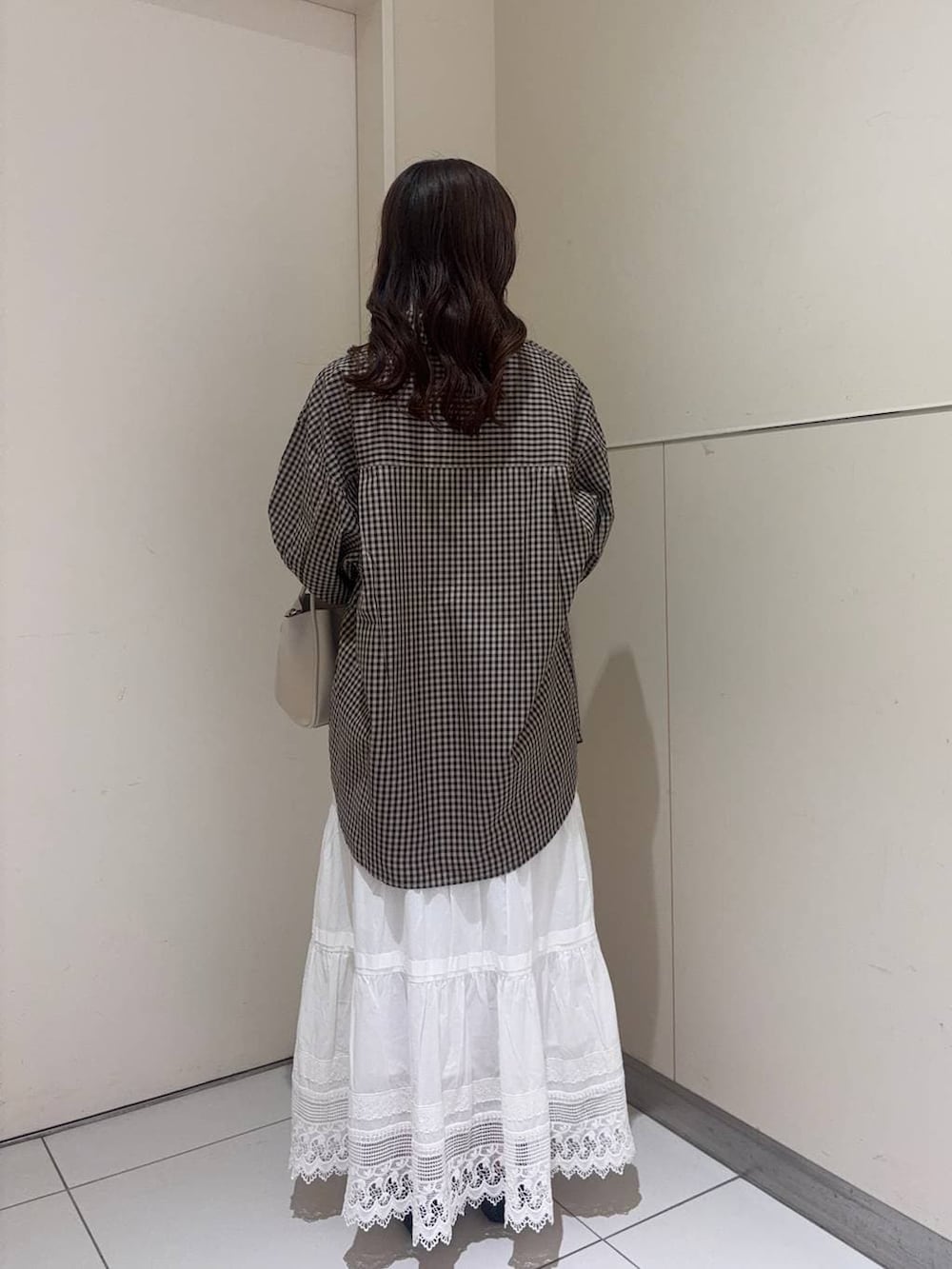 ホワイト系のショルダーバッグ、ブラック系のパンプス、ブラウン系のシャツ/ブラウスを着用したレディースの春コーディネートの3枚目の写真