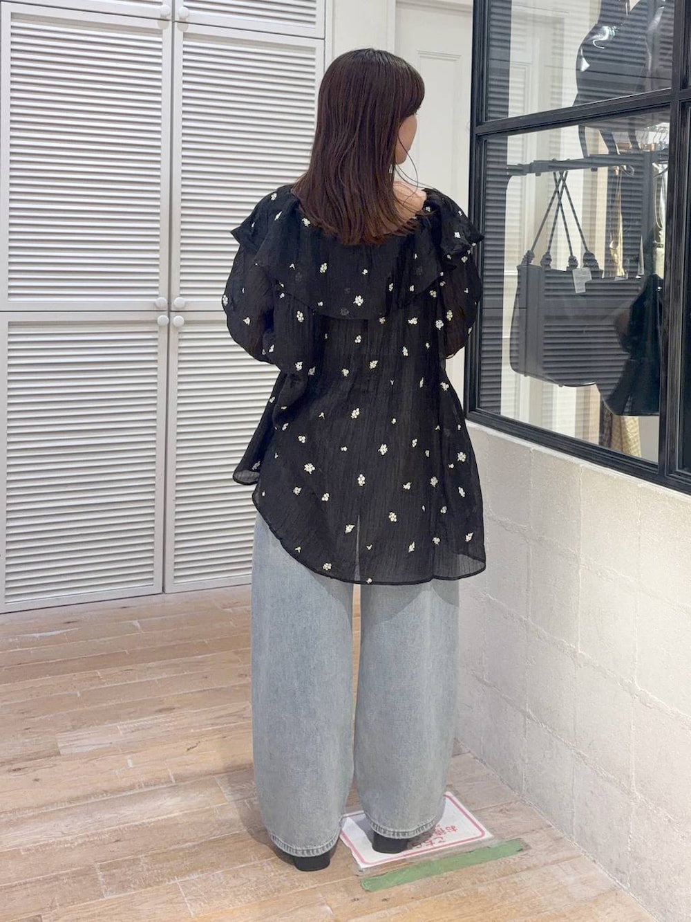 ブラック系のワンピース、ブルー系のデニムパンツ、ブラック系のサンダルを着用したレディースの夏コーディネートの3枚目の写真