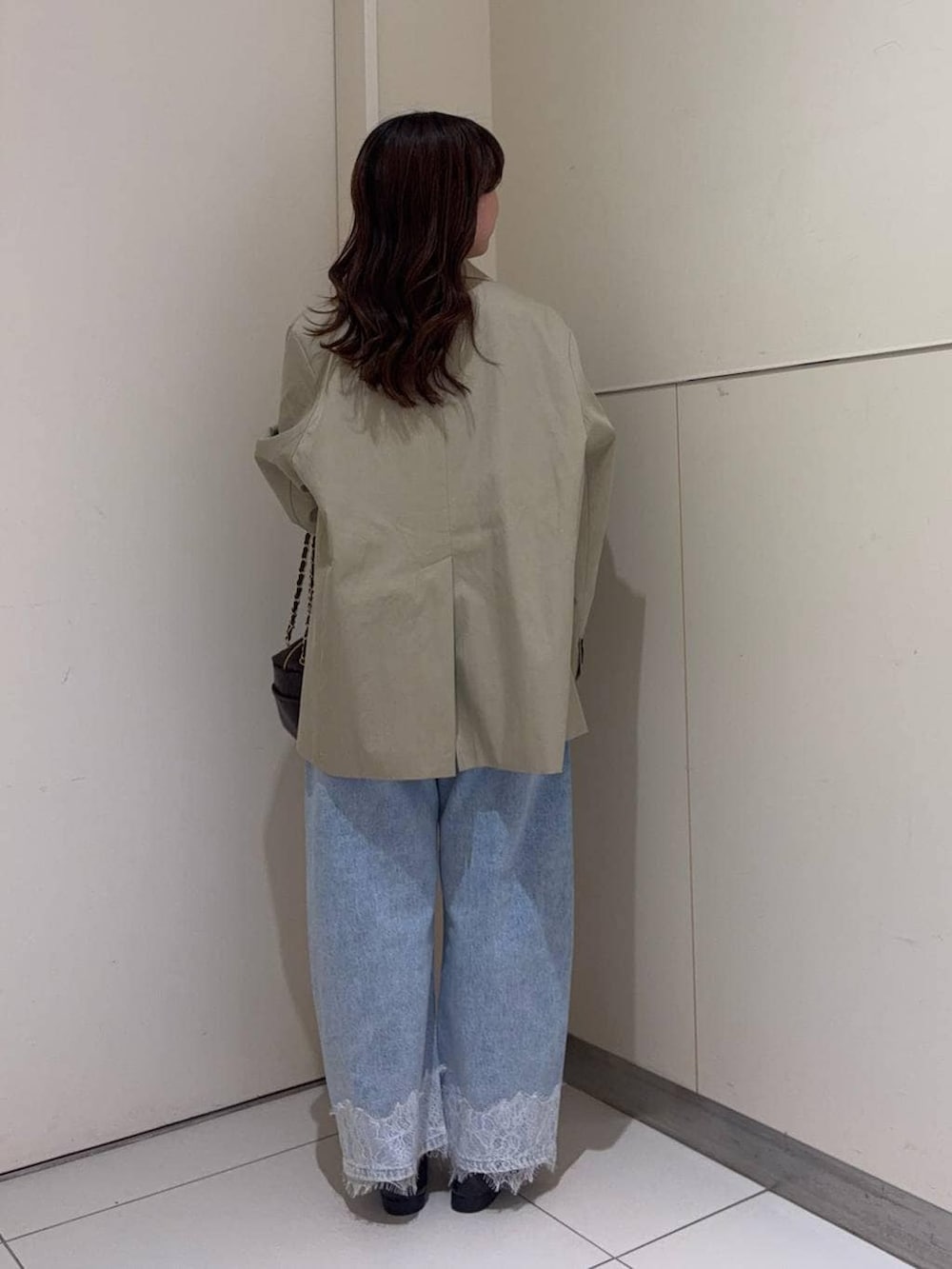 ブルー系のデニムパンツ、ブラック系のショルダーバッグ、ブラウン系のローファーを着用したレディースの春コーディネートの3枚目の写真