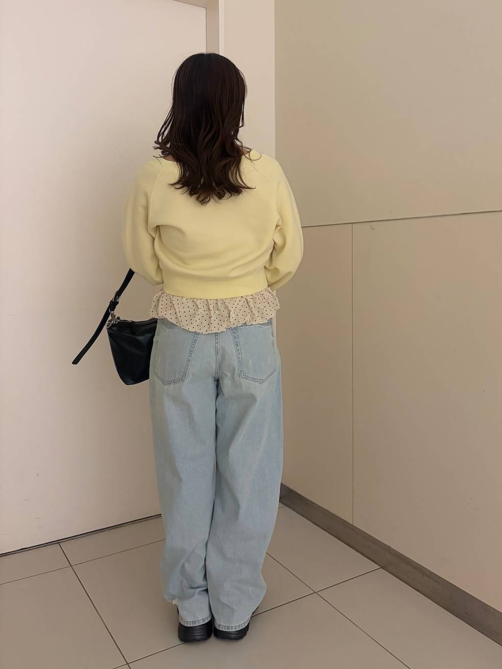 ブルー系のデニムパンツ、ブラック系のショルダーバッグ、ブラウン系のローファーを着用したレディースの春コーディネートの3枚目の写真