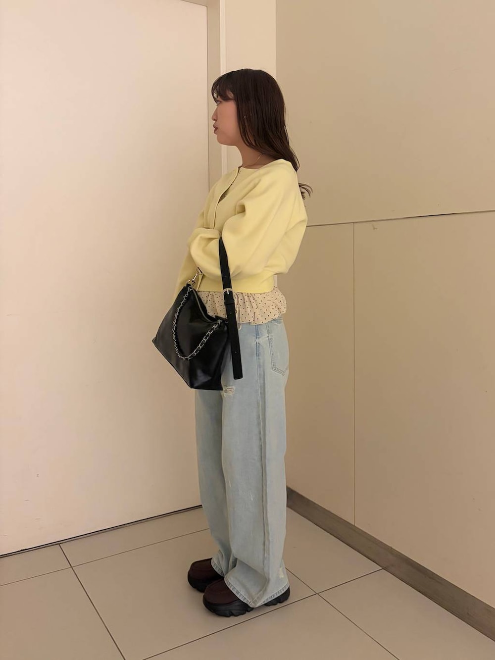ブルー系のデニムパンツ、ブラック系のショルダーバッグ、ブラウン系のローファーを着用したレディースの春コーディネートの2枚目の写真