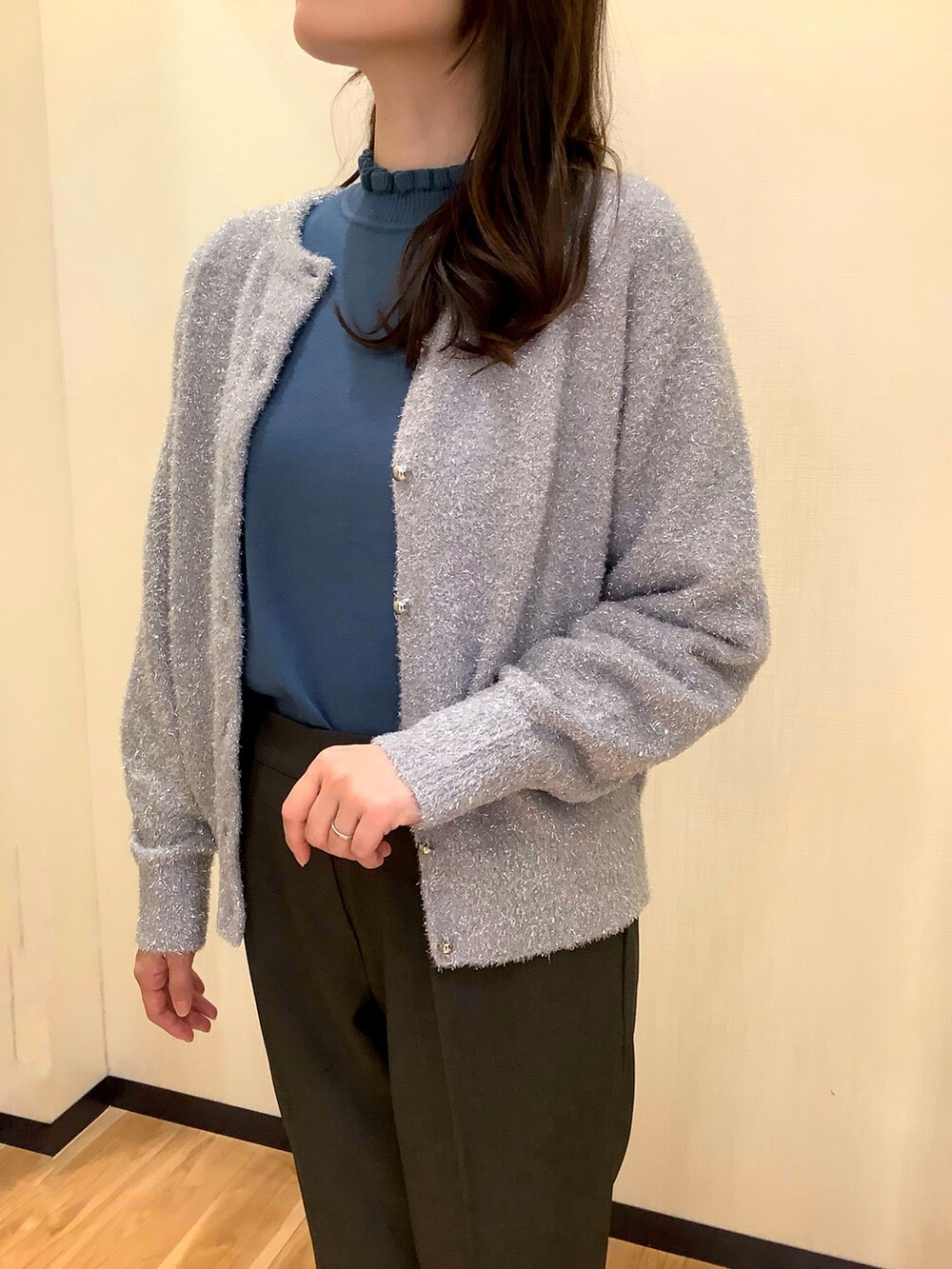 ブルー系のニット/セーター、シルバー系のカーディガン/ボレロ、グレー系のスラックスを着用したレディースの秋コーディネートの2枚目の写真