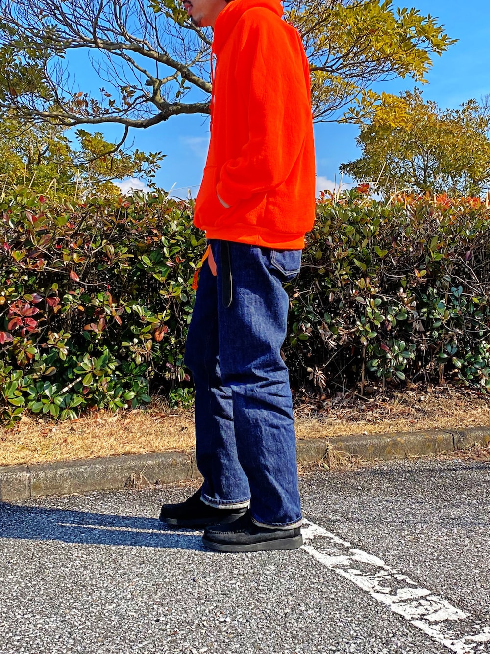 オレンジ系のパーカー、ブラック系のローファーを着用したメンズの春コーディネートの2枚目の写真