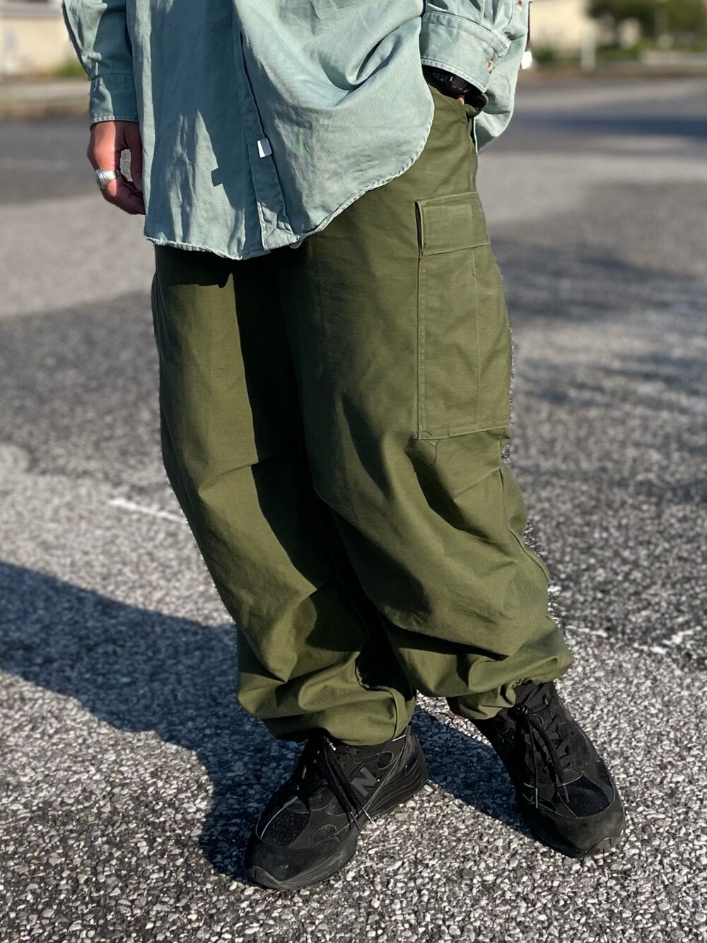 ブルー系のシャツ/ブラウス、グリーン系のカーゴパンツ、ブラック系のスニーカーを着用したメンズの春コーディネートの3枚目の写真