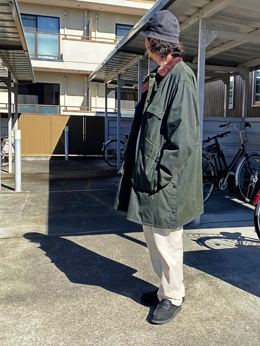 グリーン系のモッズコート、ホワイト系のチノパンツ、ブラック系のローファーを着用したメンズの冬コーディネートの2枚目の写真