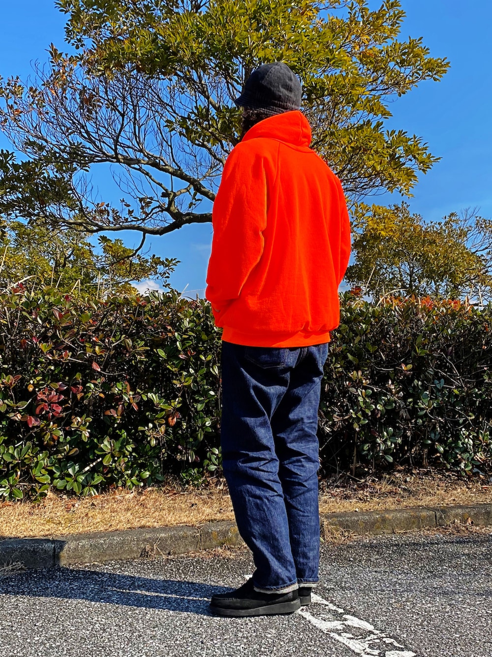 オレンジ系のパーカー、ブラック系のローファーを着用したメンズの春コーディネートの3枚目の写真