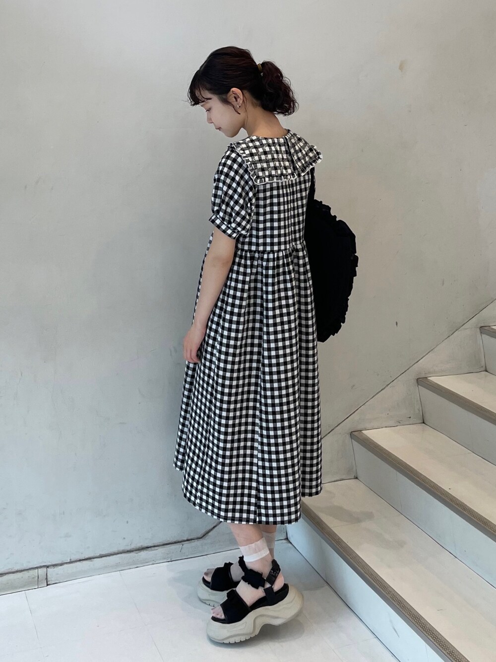 ブラック系のサンダル、ブラック系のワンピース、ブラック系のトートバッグを着用したレディースの夏コーディネートの3枚目の写真