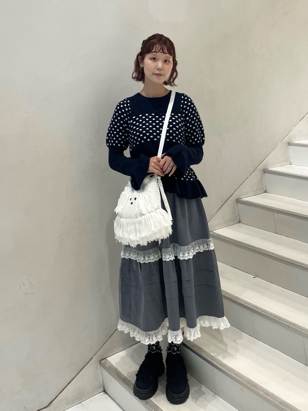 ブルー系のニット/セーター、グレー系のスカート、ホワイト系のショルダーバッグを着用したレディースの秋コーディネートの2枚目の写真