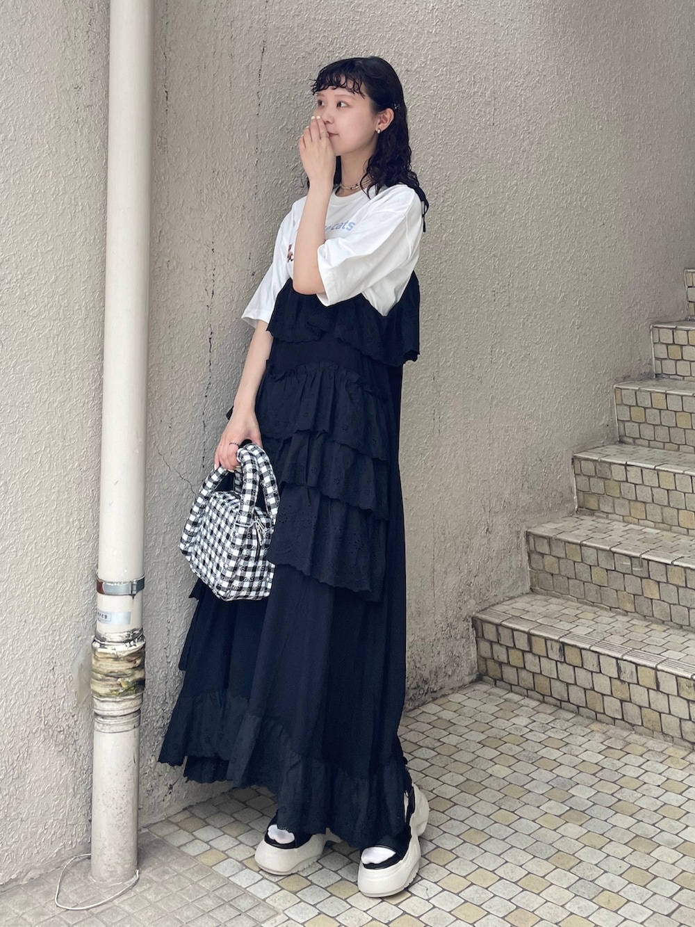 ブラック系のワンピース、ホワイト系のTシャツ/カットソー、ブラック系のサンダルを着用したレディースの夏コーディネートの2枚目の写真