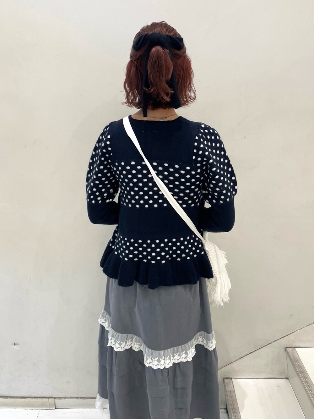 ブルー系のニット/セーター、グレー系のスカート、ホワイト系のショルダーバッグを着用したレディースの秋コーディネートの6枚目の写真