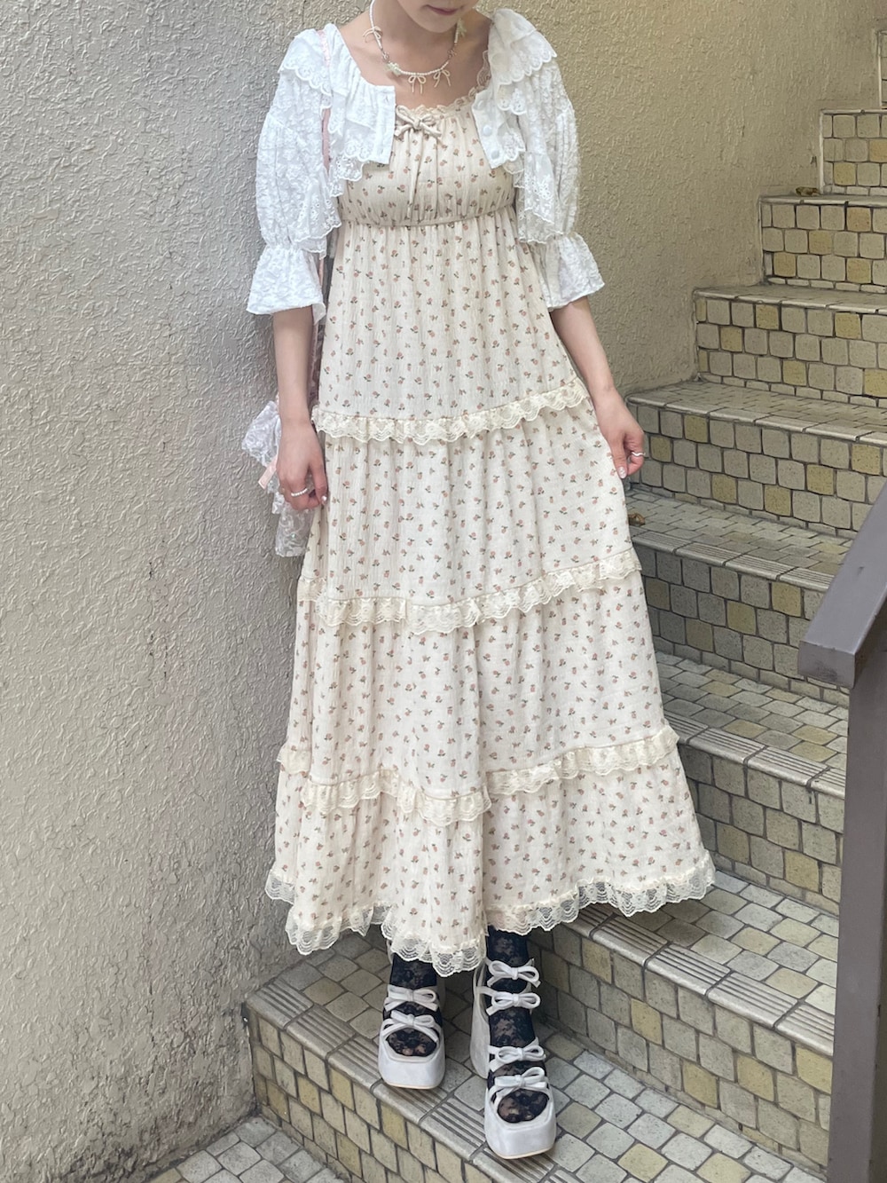 ベージュ系のワンピース、ホワイト系のカーディガン/ボレロ、ピンク系のショルダーバッグを着用したレディースの春コーディネートの2枚目の写真