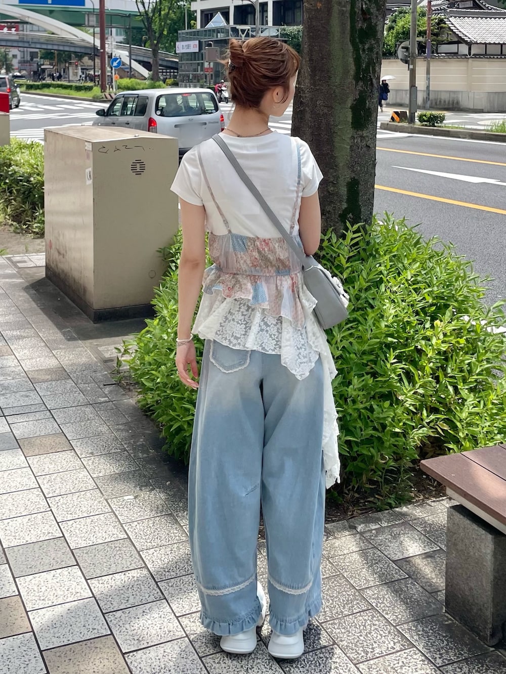 ブルー系のデニムパンツ、ブルー系のショルダーバッグ、ホワイト系のスニーカーを着用したレディースの夏コーディネートの3枚目の写真
