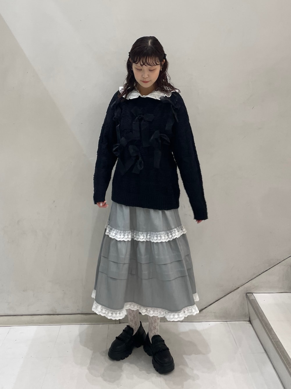 グレー系のスカート、ブラック系のダウンジャケット/コート、ブラック系のニット/セーターを着用したレディースの冬コーディネートの3枚目の写真