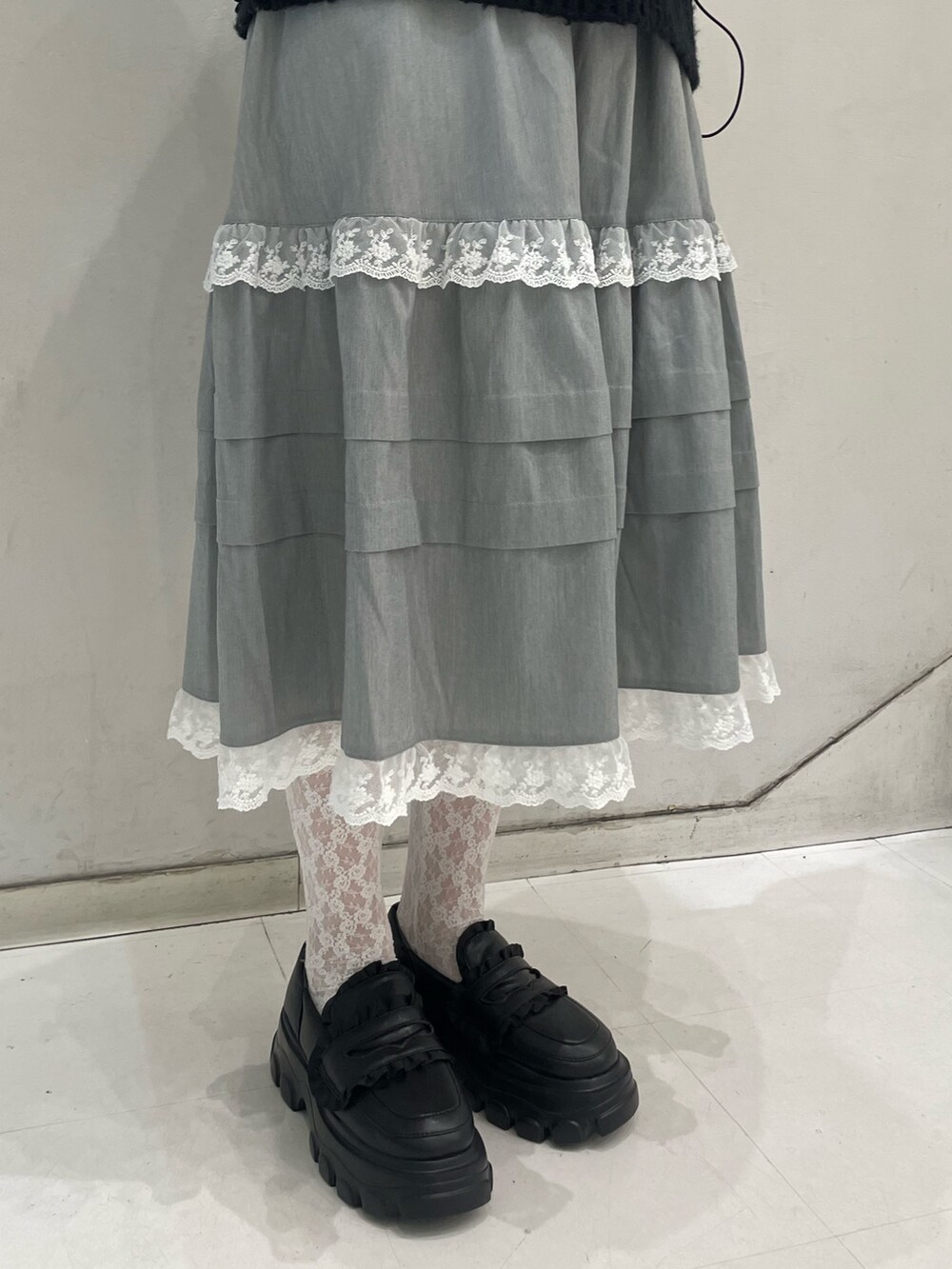 グレー系のスカート、ブラック系のダウンジャケット/コート、ブラック系のニット/セーターを着用したレディースの冬コーディネートの7枚目の写真