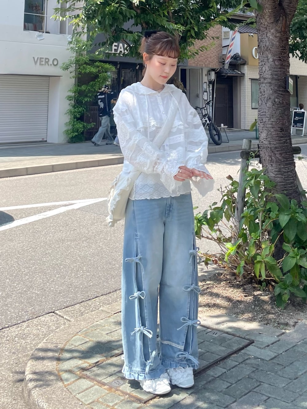 ホワイト系のシャツ/ブラウス、グリーン系のスニーカー、ブルー系のデニムパンツを着用したレディースの夏コーディネートの3枚目の写真