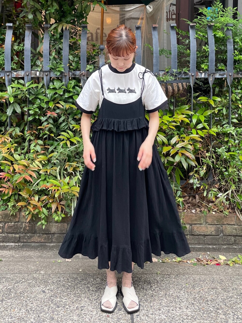 ブラック系のスカート、ホワイト系のTシャツ/カットソー、グレー系のサンダルを着用したレディースの春コーディネートの2枚目の写真