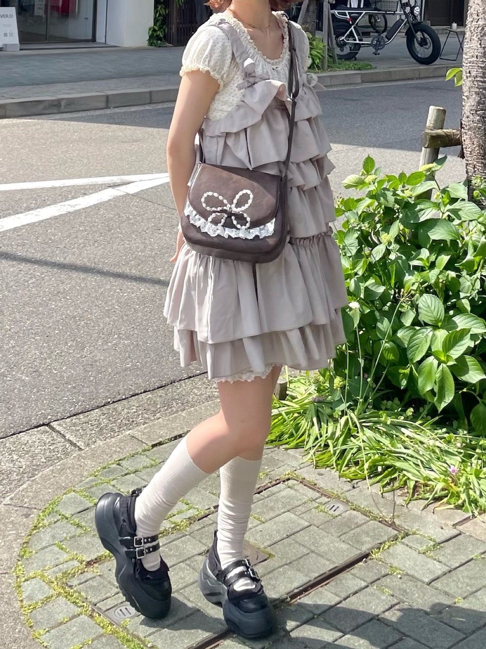 ホワイト系のTシャツ/カットソー、ブラック系のスニーカー、ブラウン系のショルダーバッグを着用したレディースの春コーディネートの2枚目の写真