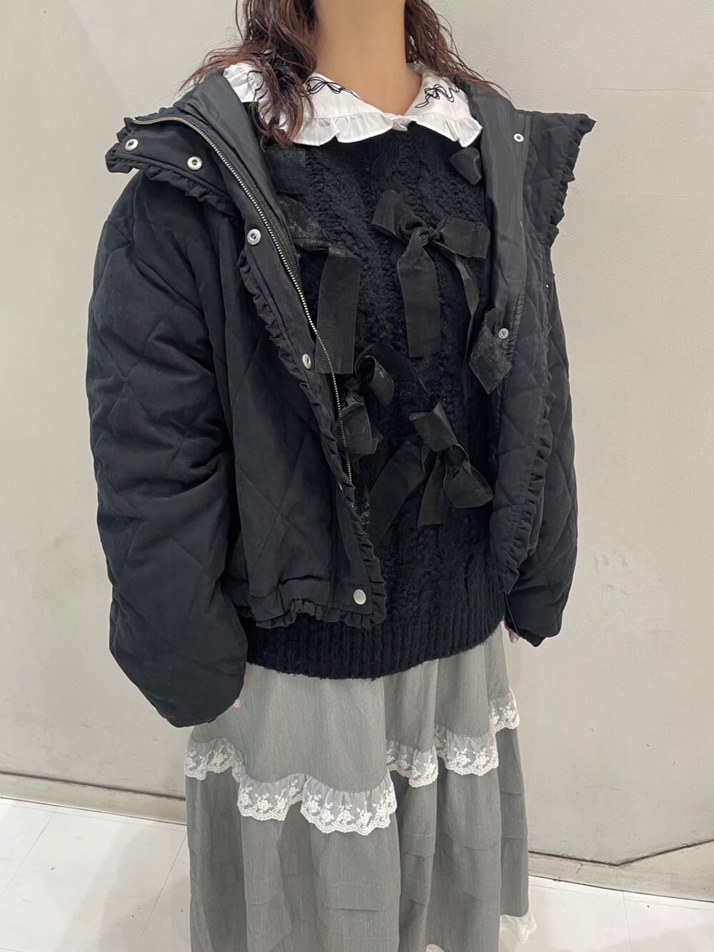 グレー系のスカート、ブラック系のダウンジャケット/コート、ブラック系のニット/セーターを着用したレディースの冬コーディネートの6枚目の写真