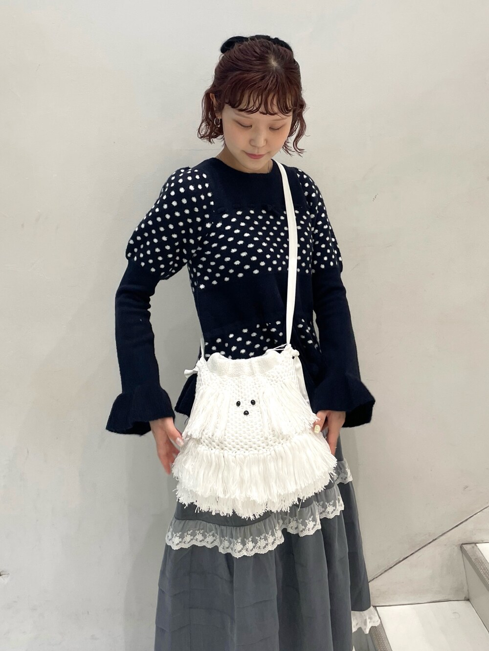 ブルー系のニット/セーター、グレー系のスカート、ホワイト系のショルダーバッグを着用したレディースの秋コーディネートの5枚目の写真