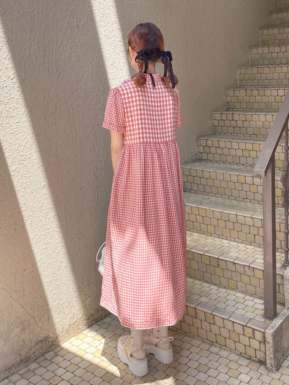 レッド系のワンピース、ホワイト系のショルダーバッグ、ホワイト系のサンダルを着用したレディースの春コーディネートの3枚目の写真