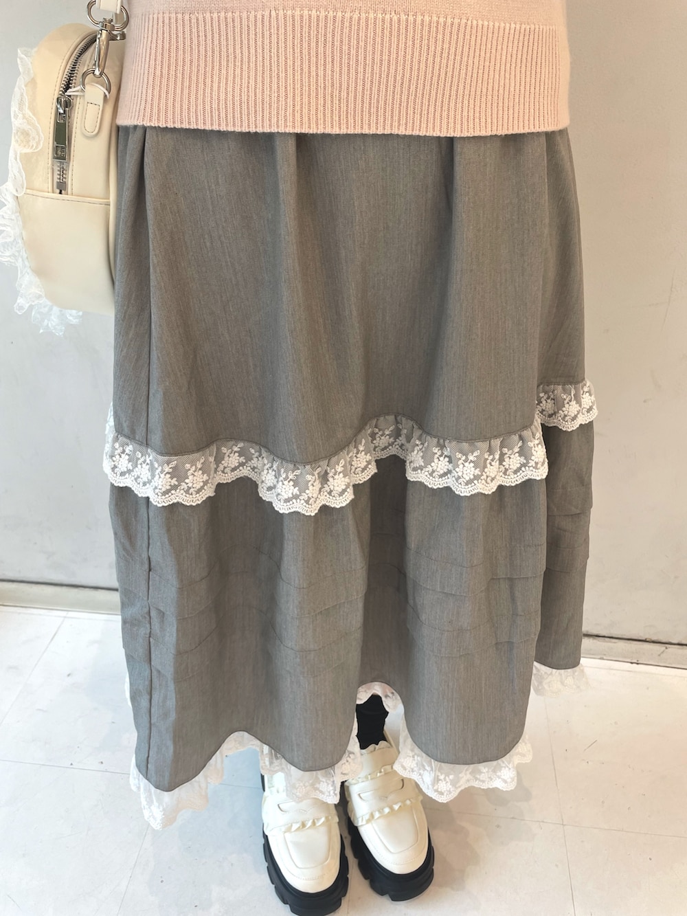 ピンク系のニット/セーター、グレー系のスカート、ホワイト系のショルダーバッグを着用したレディースの秋コーディネートの6枚目の写真