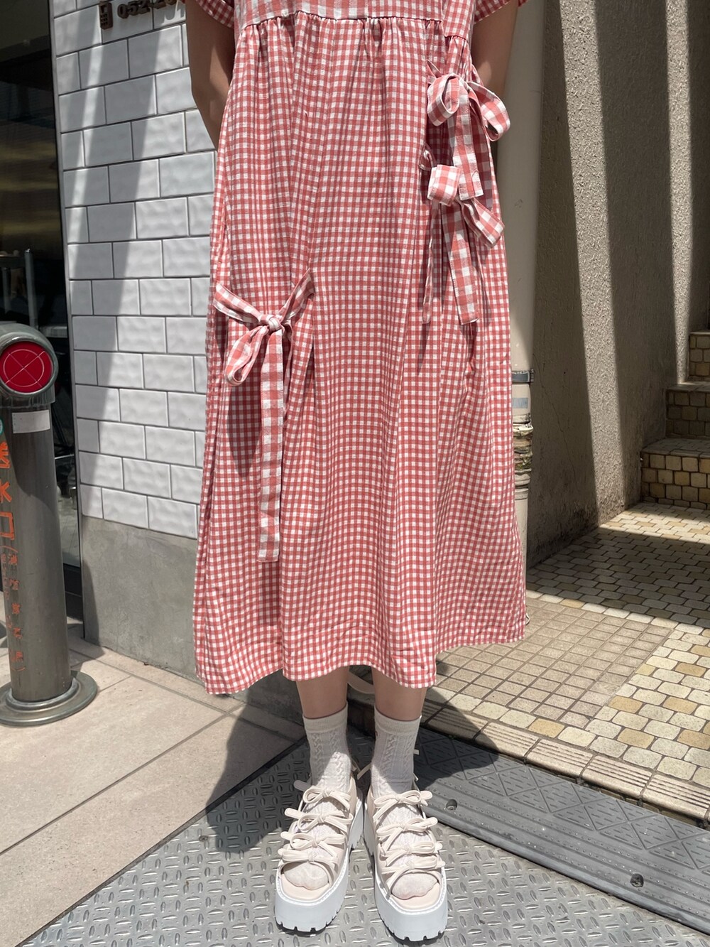 レッド系のワンピース、ホワイト系のショルダーバッグ、ホワイト系のサンダルを着用したレディースの春コーディネートの9枚目の写真