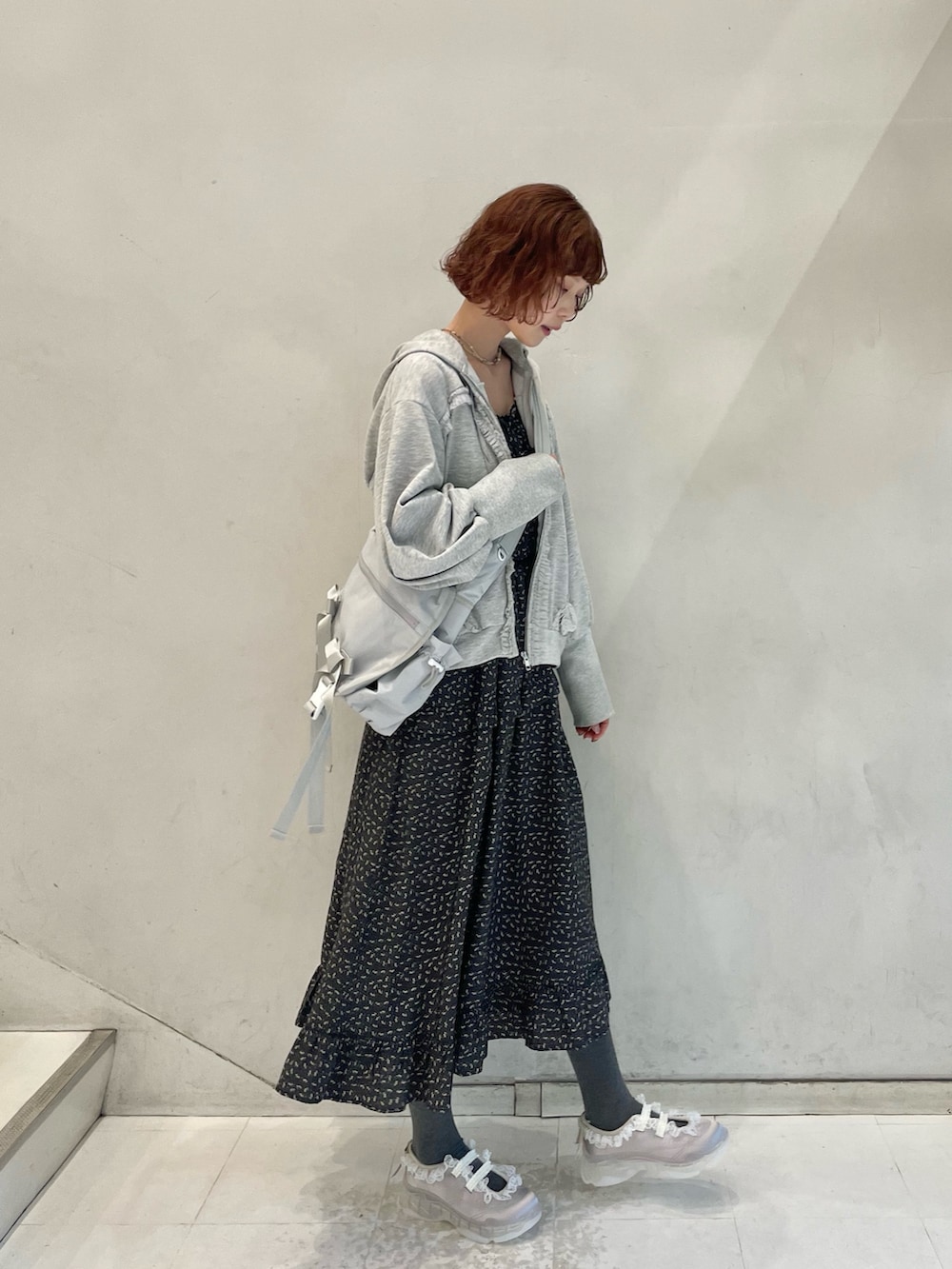 グレー系のパーカー、グレー系のメッセンジャーバッグ、ブラック系のワンピースを着用したレディースの冬コーディネートの4枚目の写真