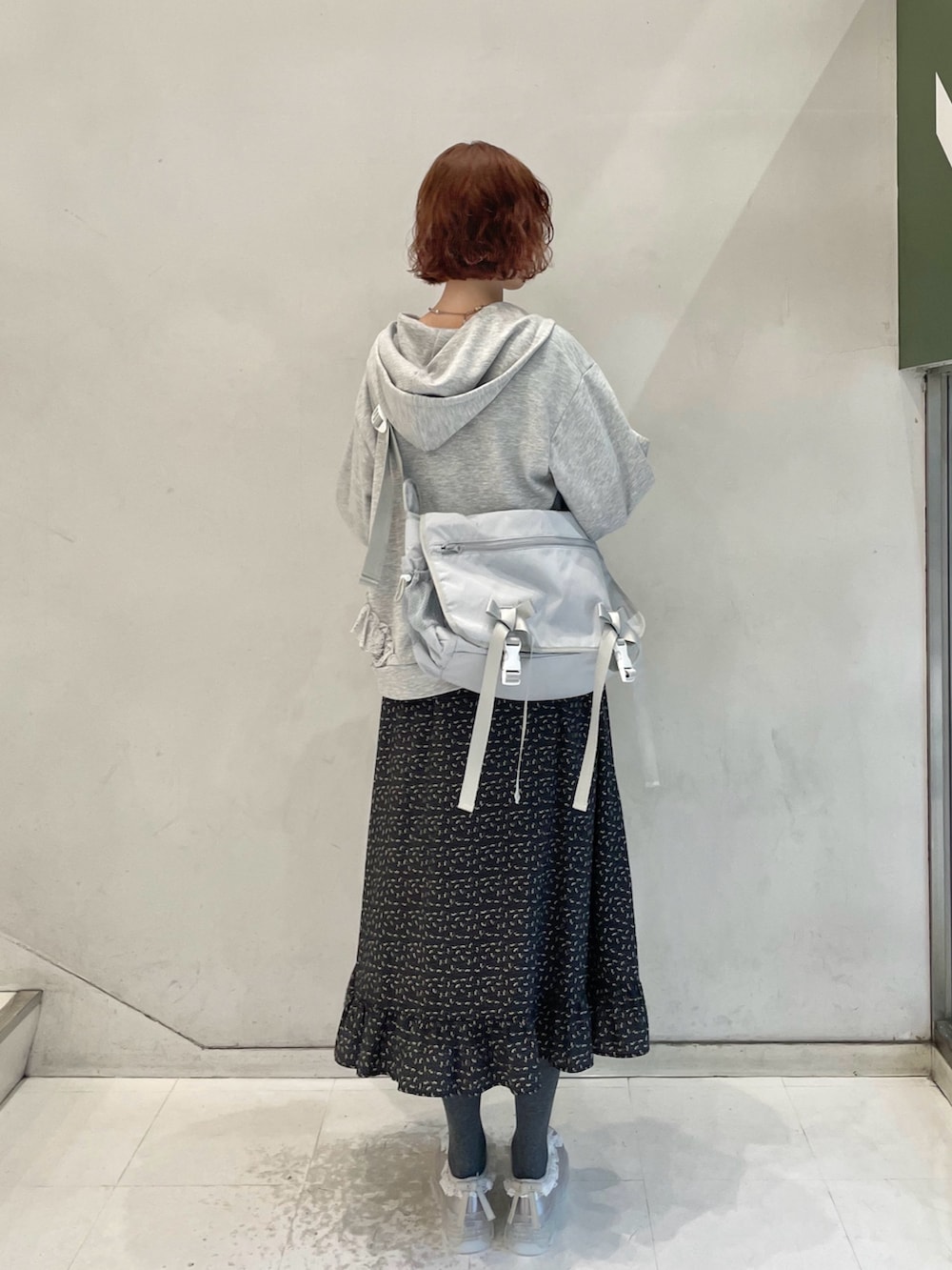 グレー系のパーカー、グレー系のメッセンジャーバッグ、ブラック系のワンピースを着用したレディースの冬コーディネートの3枚目の写真