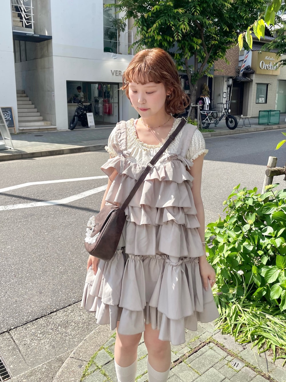 ホワイト系のTシャツ/カットソー、ブラック系のスニーカー、ブラウン系のショルダーバッグを着用したレディースの春コーディネートの5枚目の写真