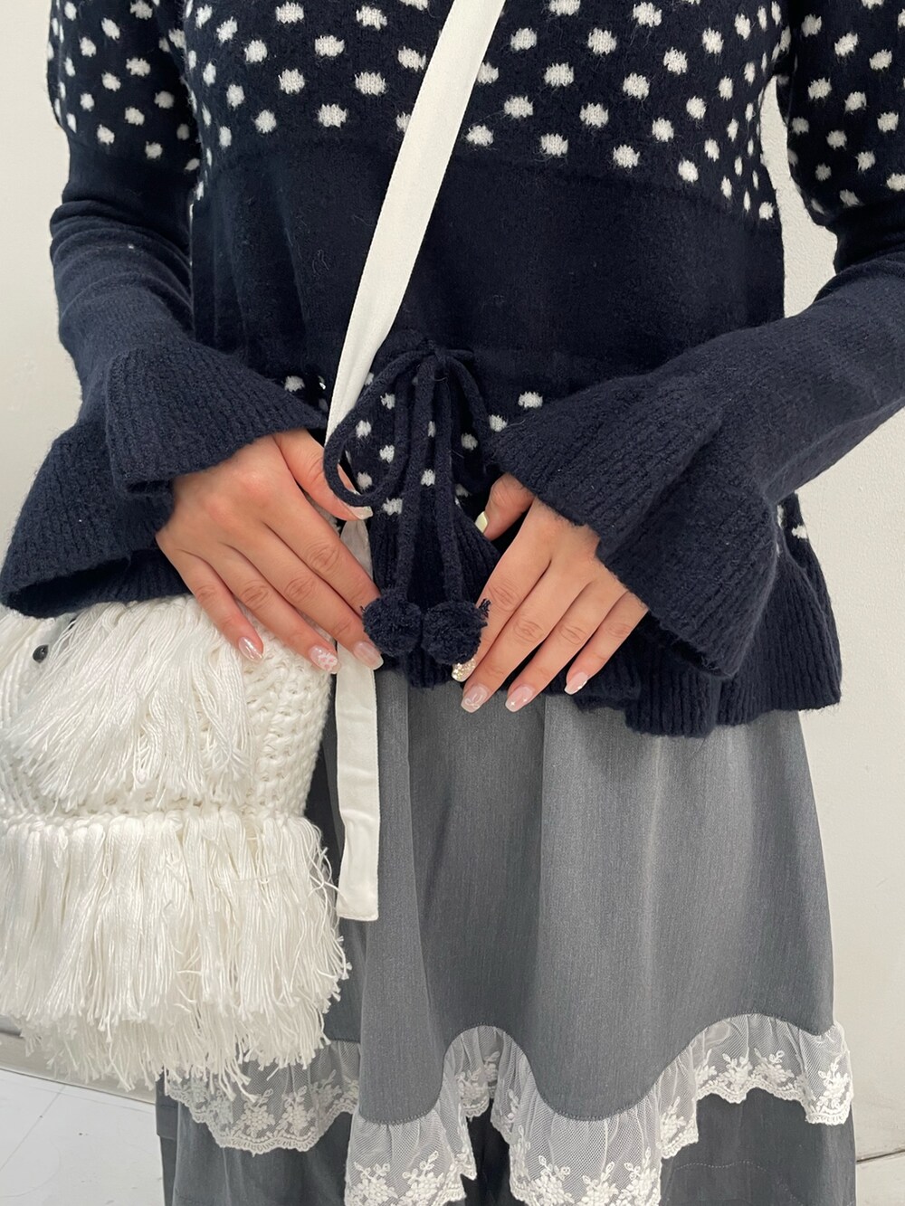 ブルー系のニット/セーター、グレー系のスカート、ホワイト系のショルダーバッグを着用したレディースの秋コーディネートの7枚目の写真