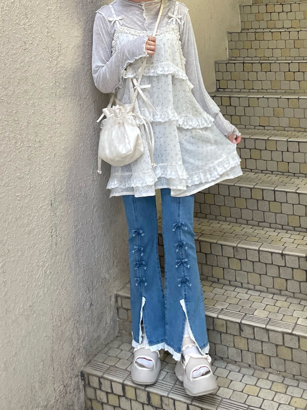 ブルー系のデニムパンツ、グレー系のTシャツ/カットソー、ホワイト系のサンダルを着用したレディースの夏コーディネートの2枚目の写真
