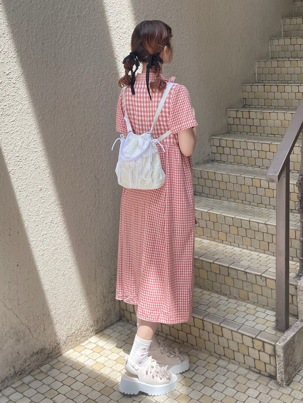 レッド系のワンピース、ホワイト系のショルダーバッグ、ホワイト系のサンダルを着用したレディースの春コーディネートの5枚目の写真